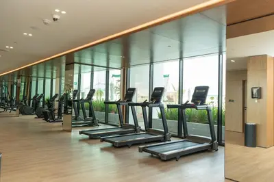 a row of treadmills in a gym with windows at Binghatti Amber in JVC, 15 Min to Marina in Dubai
