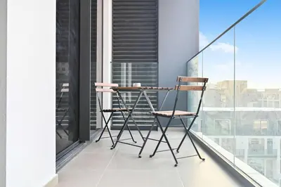 a chair on a balcony with a view of a city at Modern 1BR w Balcony & Great Amenities JVC in Dubai