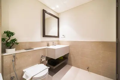 a bathroom with a sink and a toilet and a mirror at SettlerHomes - 14F Ocean View Gem With Private Beach in Dubai
