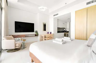 a white bedroom with a large bed and a tv at Silkhaus Studio Escape in Business Bay in Dubai
