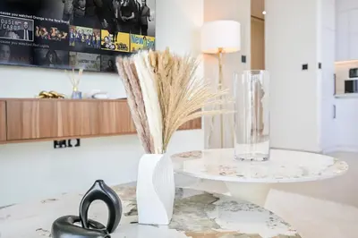 a table with a vase of dry grass and a glass at Golden Stays - Private Pool in Binghatti Gardenia I Modern 2BR Escape in Dubai
