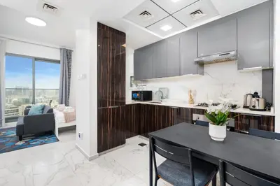 a kitchen with a table and a dining room at White Sage Modern Studio in JVC with Balcony and City Views in Dubai