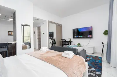 a white bedroom with a bed and a couch at White Sage Modern Studio in JVC with Balcony and City Views in Dubai