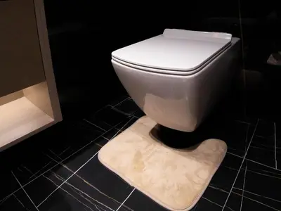 a white toilet in a bathroom with a rug at Binghatti Corner in Dubai