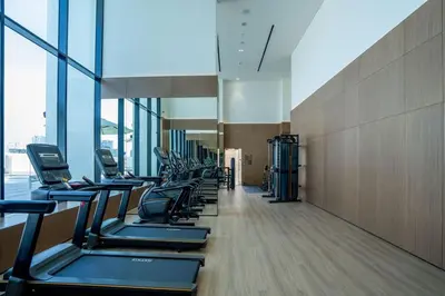 a row of treadmills in a gym with windows at Modern 1BR Apt in Binghatti Gardenia with Pool & Gym! in Dubai