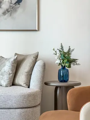 a living room with a chair and a vase of flowers on a table at Elegant 2BR, Grand Bleu, Coastal Elegance in Dubai