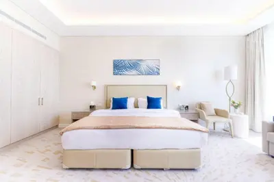a white bedroom with a large bed with blue pillows at Sky-High Elegant Suite at Palm Tower in Dubai
