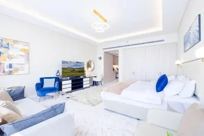 a white bedroom with a large bed and a blue chair at Sky-High Elegant Suite at Palm Tower in Dubai