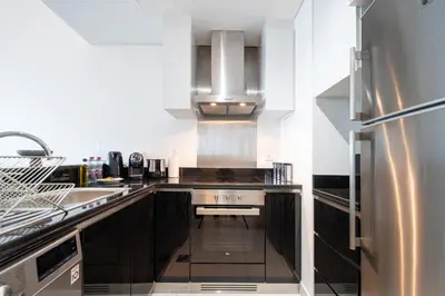 a kitchen with black cabinets and a stainless steel refrigerator at High-Floor Elegance | 1-Bedroom with Marina Views in Dubai