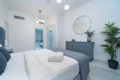 a white bedroom with a large bed and a mirror at High-Floor Elegance | 1-Bedroom with Marina Views in Dubai