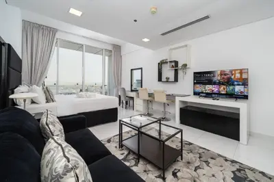 a living room with a bed and a tv at Sleek and Spacious Sports City Studio in Dubai