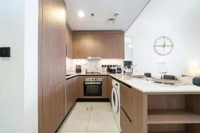 a kitchen with wooden cabinets and a dishwasher at Stylish Studio in JVC Bright, Cozy and Convenient in Dubai