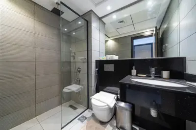 a bathroom with a toilet and a sink and a shower at Modern JVC 1-Bed Pool, Gym and Family Amenities in Dubai