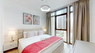 a white bedroom with a large bed with a red blanket at Vacationer Chic 1 Bedroom Creek Harbour in Dubai