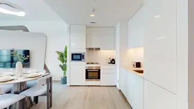 a kitchen and dining room with white cabinets and a table at Vacationer Chic 1 Bedroom Creek Harbour in Dubai