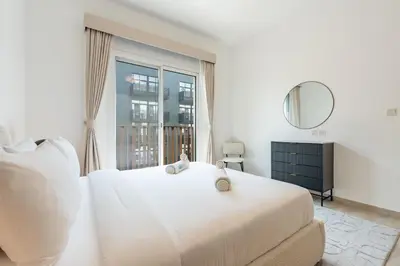 a white bedroom with a large bed and a window at Contemporary 1Bedroom Escape in Eaton Place in Dubai