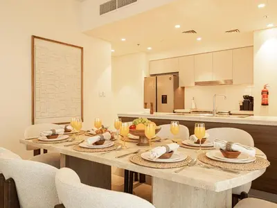a dining room with a table and chairs and a kitchen at Forte Suites by Prestige Nest in Dubai