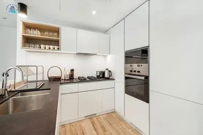 a kitchen with white cabinets and stainless steel appliances at Cozy 2-BR at Belgravia Square in Dubai