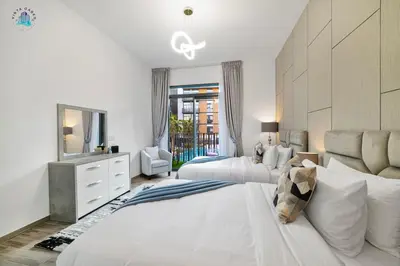 a white bedroom with two beds and a mirror at Cozy 2-BR at Belgravia Square in Dubai