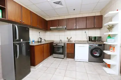 a kitchen with stainless steel appliances and wooden cabinets at Cozy Master Bedroom with private bathroom and private balcony in Dubai