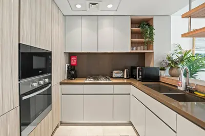 a kitchen with white cabinets and a stove top oven at One Park Avenue, Sobha Hartland 3 BR in Dubai