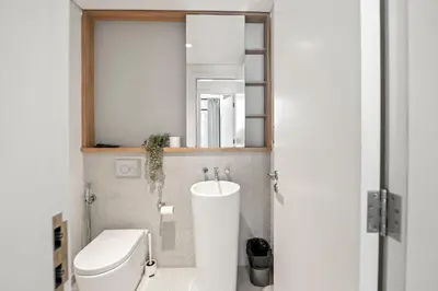 a bathroom with a toilet and a sink and a mirror at One Park Avenue, Sobha Hartland 3 BR in Dubai