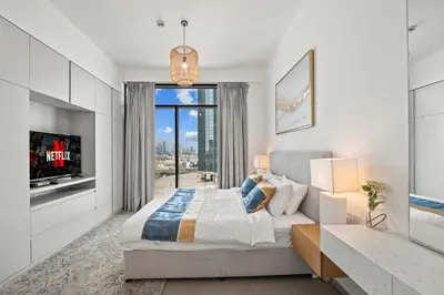 a bedroom with a large bed and a tv at One Park Avenue, Sobha Hartland 3 BR in Dubai