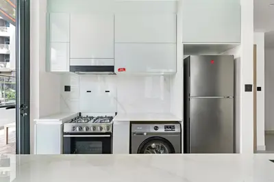 a kitchen with white cabinets and a stainless steel refrigerator at Burj Khalifa View 2BR at Binghatti Canal in Dubai