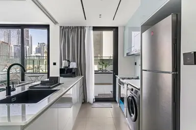 a kitchen with a sink and a refrigerator at Burj Khalifa View 2BR at Binghatti Canal in Dubai