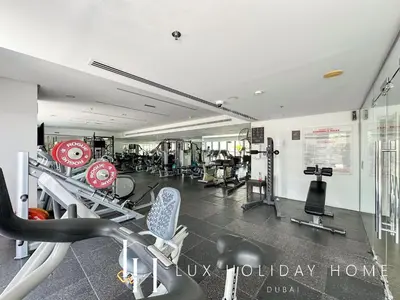 a gym with several treadmills and machines in it at LUX The West Avenue Dubai Marina Suite in Dubai