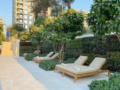 a row of lounge chairs and trees in a garden at FIRST CLASS 2BR Creek Beach Comfort & Style in Dubai