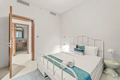 a white bedroom with a bed and a bathroom at FIRST CLASS 2BR Creek Beach Comfort & Style in Dubai