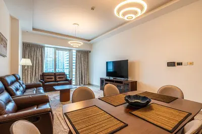 a living room with a table and chairs and a television at Spacious 2 Bedrooms with maid room I JLT in Dubai