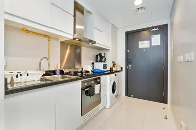 a kitchen with a sink and a washing machine at White Sage Damac Hills Cozy Artesia Studio in Dubai