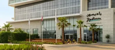 a building with palm trees in front of it at White Sage Damac Hills Cozy Artesia Studio in Dubai