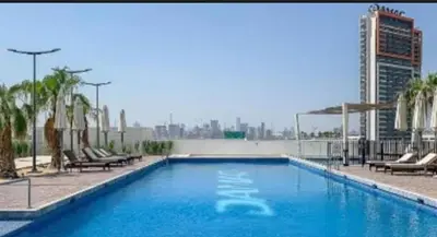 a large blue swimming pool with chairs and a city at White Sage Damac Hills Cozy Artesia Studio in Dubai