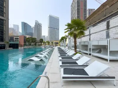 a row of chaise lounges in a pool on a building at GuestReady - 1BR l Canal View | Near Dubai Mall in Dubai