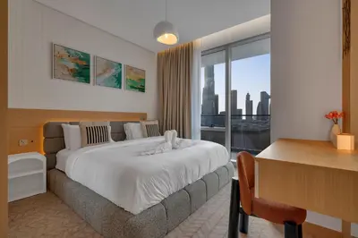 a hotel room with a bed and a desk and a window at Burj View Direct to Dubai Mall 2BR in Dubai