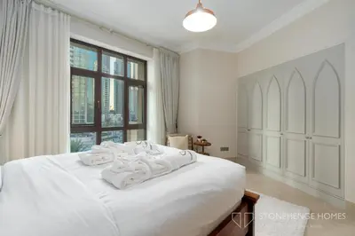 a white bedroom with a large white bed and a window at Chic 1BR Apartment in Downtown Dubai Steps Away from Burj Khalifa & Dubai Mall in Dubai