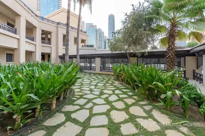 a walkway in the courtyard of a building with palm trees at Chic 1BR Apartment in Downtown Dubai Steps Away from Burj Khalifa & Dubai Mall in Dubai