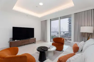 a living room with a tv and a couch and chairs at Luxury 1 Bedroom in Emaar Beach Front - Dubai Marina - Private Beach in Dubai