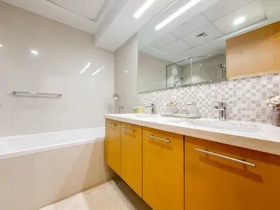 a bathroom with yellow cabinets and a tub and a sink at Zinnia Luxury 2BHK Bellevue Burj Khalifa View in Dubai