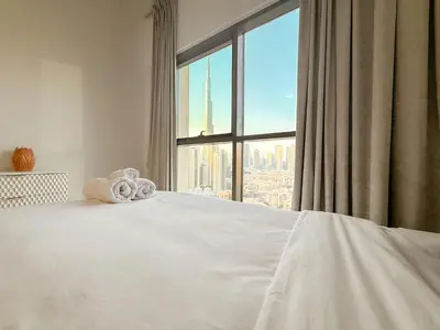 a bedroom with a white bed with a large window at Zinnia Luxury 2BHK Bellevue Burj Khalifa View in Dubai