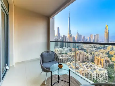 a chair and a glass table in a room with a large window at Zinnia Luxury 2BHK Bellevue Burj Khalifa View in Dubai