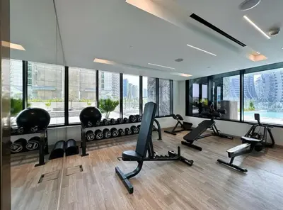 a gym with treadmills and ellipticals in a room with windows at Water Dream with Burj Views Sleeps 4 in Dubai