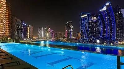 a large swimming pool with a city skyline at night at Water Dream with Burj Views Sleeps 4 in Dubai