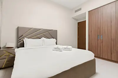 a bedroom with a large white bed and a wooden cabinet at FIRST CLAS 1BR Creek Beach , Lagoon Access in Dubai