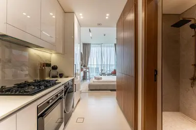 a kitchen with white cabinets and a stove at HAVN - Bright & Cozy Studio at Binghatti Azure JVC in Dubai