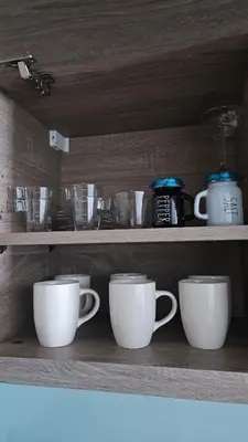 a row of cups sitting on a wooden shelf at Modern New Sea View 1 BR Apartment in Dubai