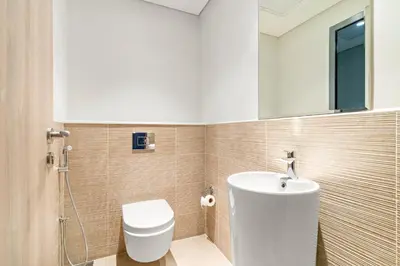 a bathroom with a toilet and a sink and a mirror at VayK - Prestigious 1BR Apartment in Dubai Hills Estate in Dubai